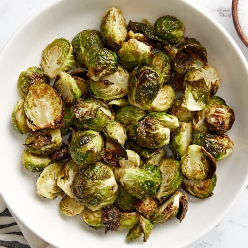 Overhead view of air fryer brussels sprouts in a white serving dish.