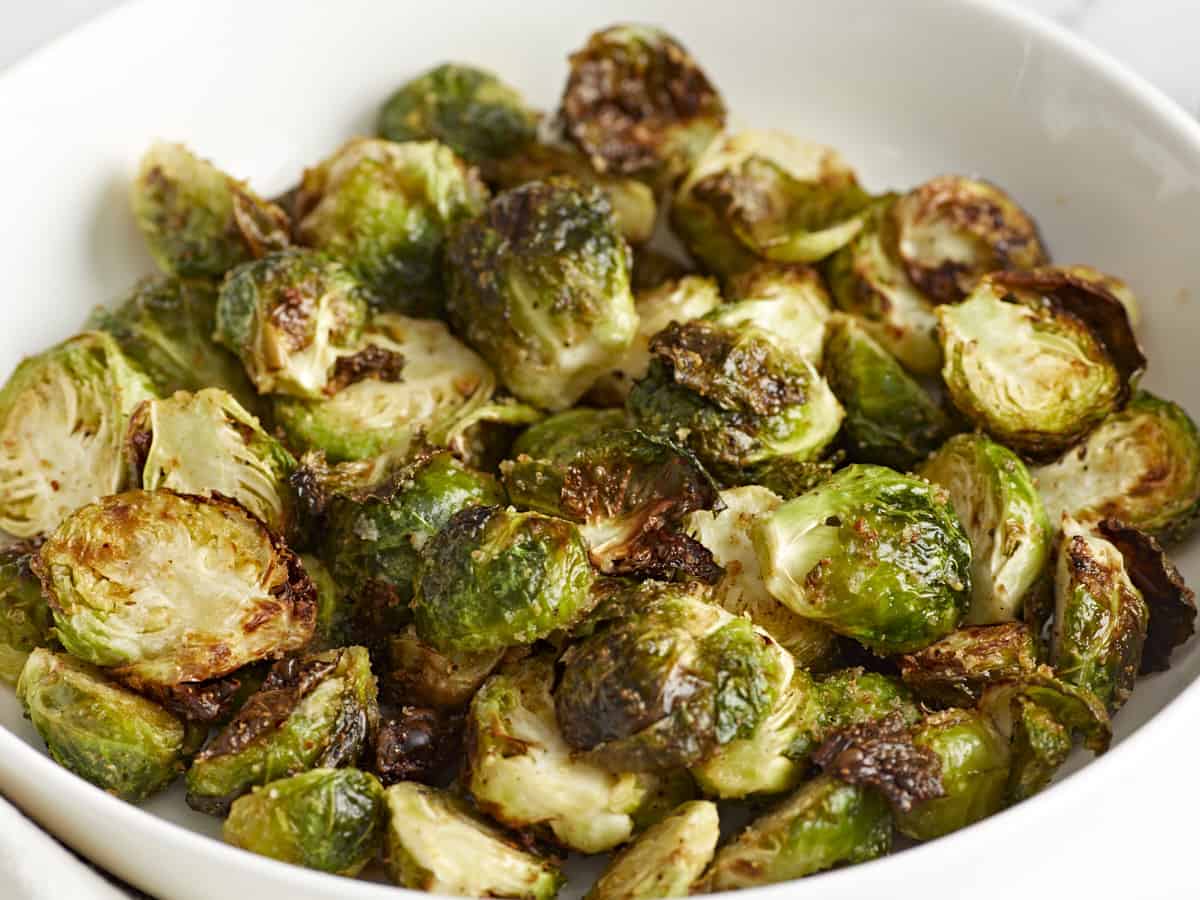 Side front view of air fryer Brussels sprouts in a white serving dish.