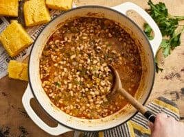 Overhead view of a pot of black-eyed peas with a wooden spoon.