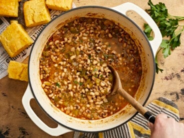 Overhead view of a pot of black-eyed peas with a wooden spoon.