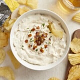 Overhead view of a bowl of French Onion Dip with a chip in the side and chips all around.