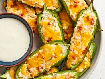 Super close up view of jalapeño poppers on a plate with a bowl of ranch.