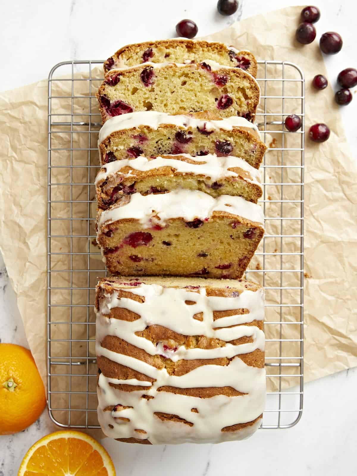Overhead view of a sliced loaf of cranberry orange bread on a cooling rack.