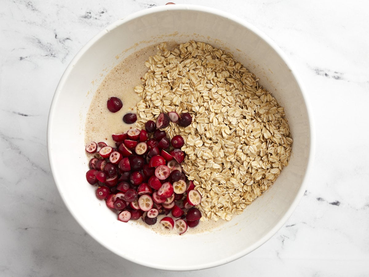 Sliced cranberries and dry oats added to the bowl.