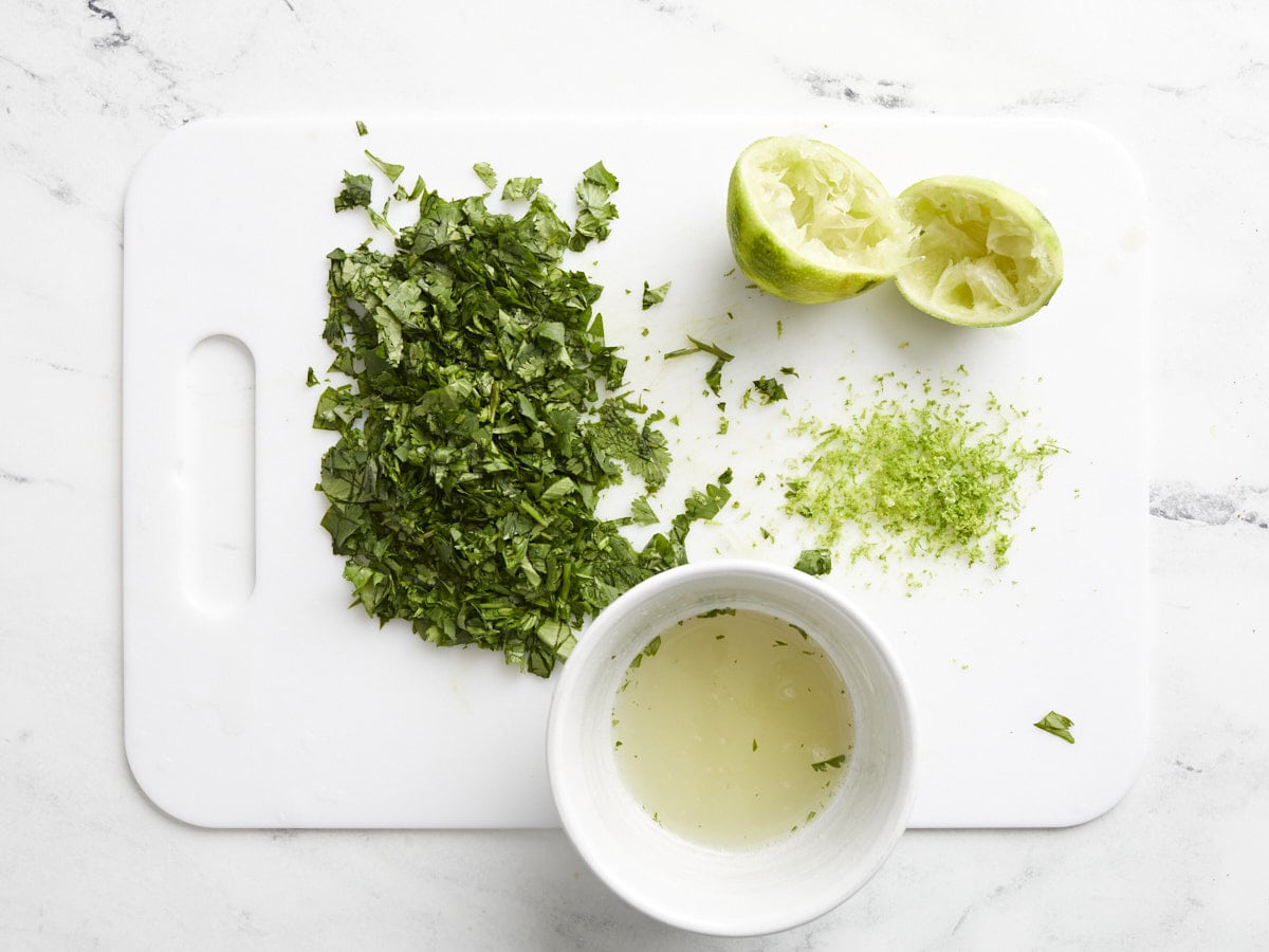 Chopped cilantro and zested and juiced lime on a cutting board. 