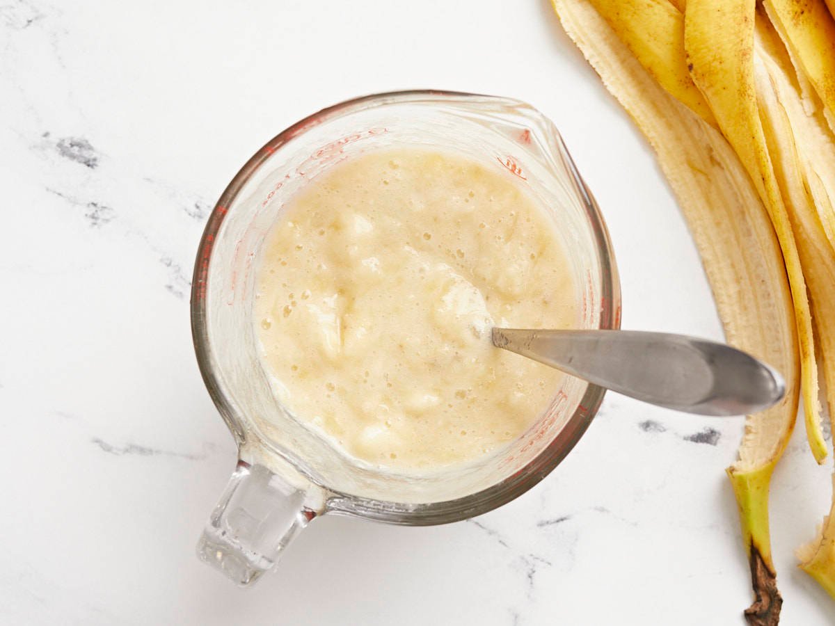 Mashed bananas in a measuring cup with a fork.