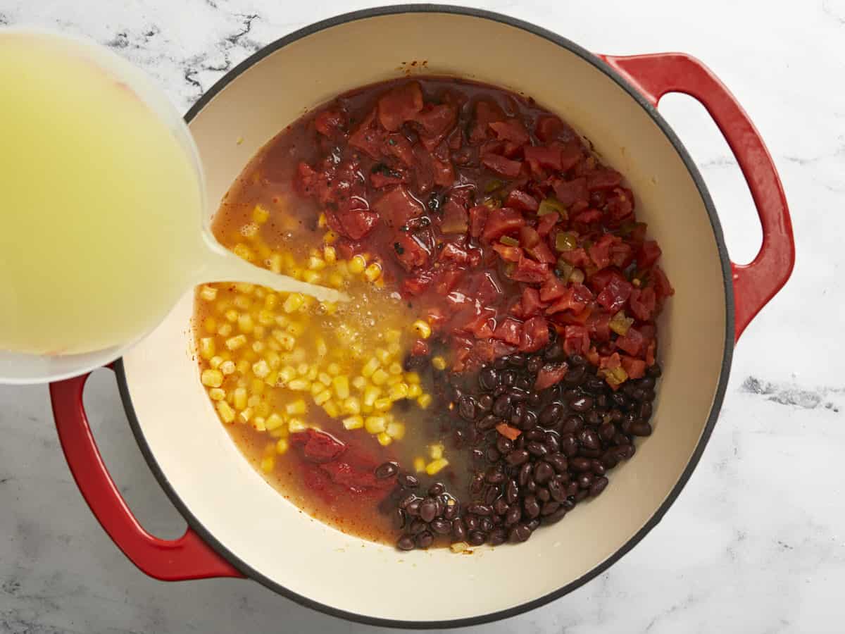 Tomatoes, black beans, corn, tomato paste, and chicken broth added to the dutch oven.