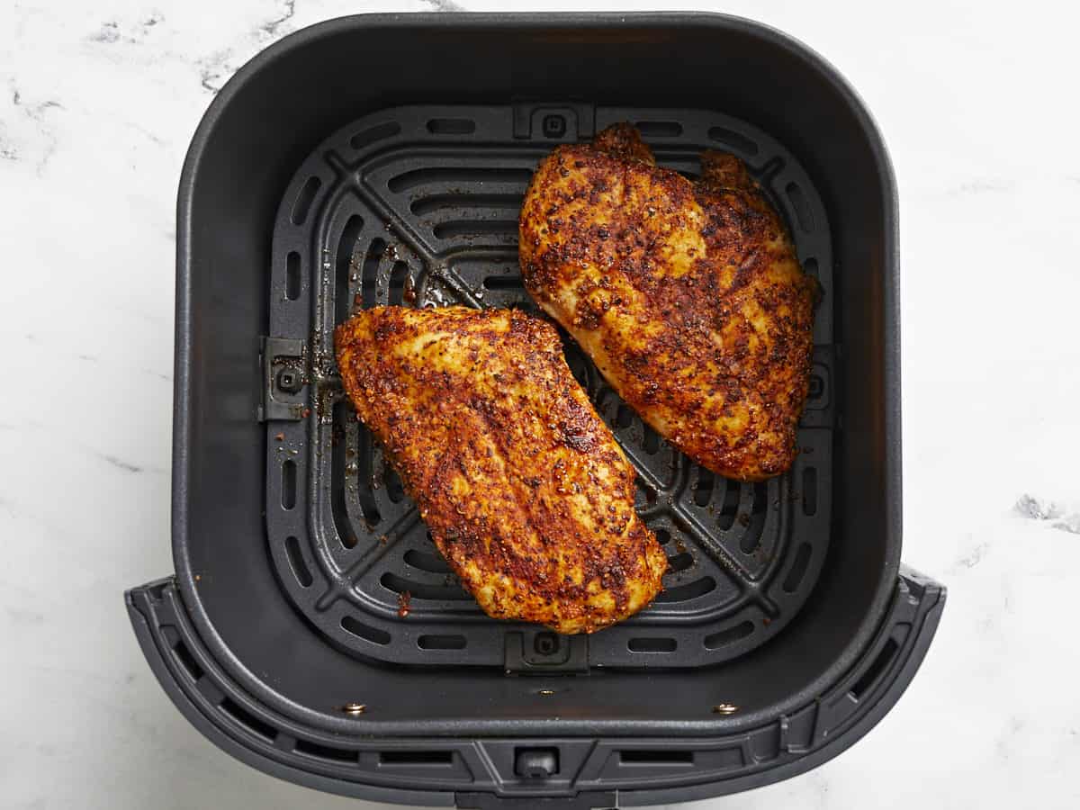 Cooked chicken breasts inside an air fryer basket.