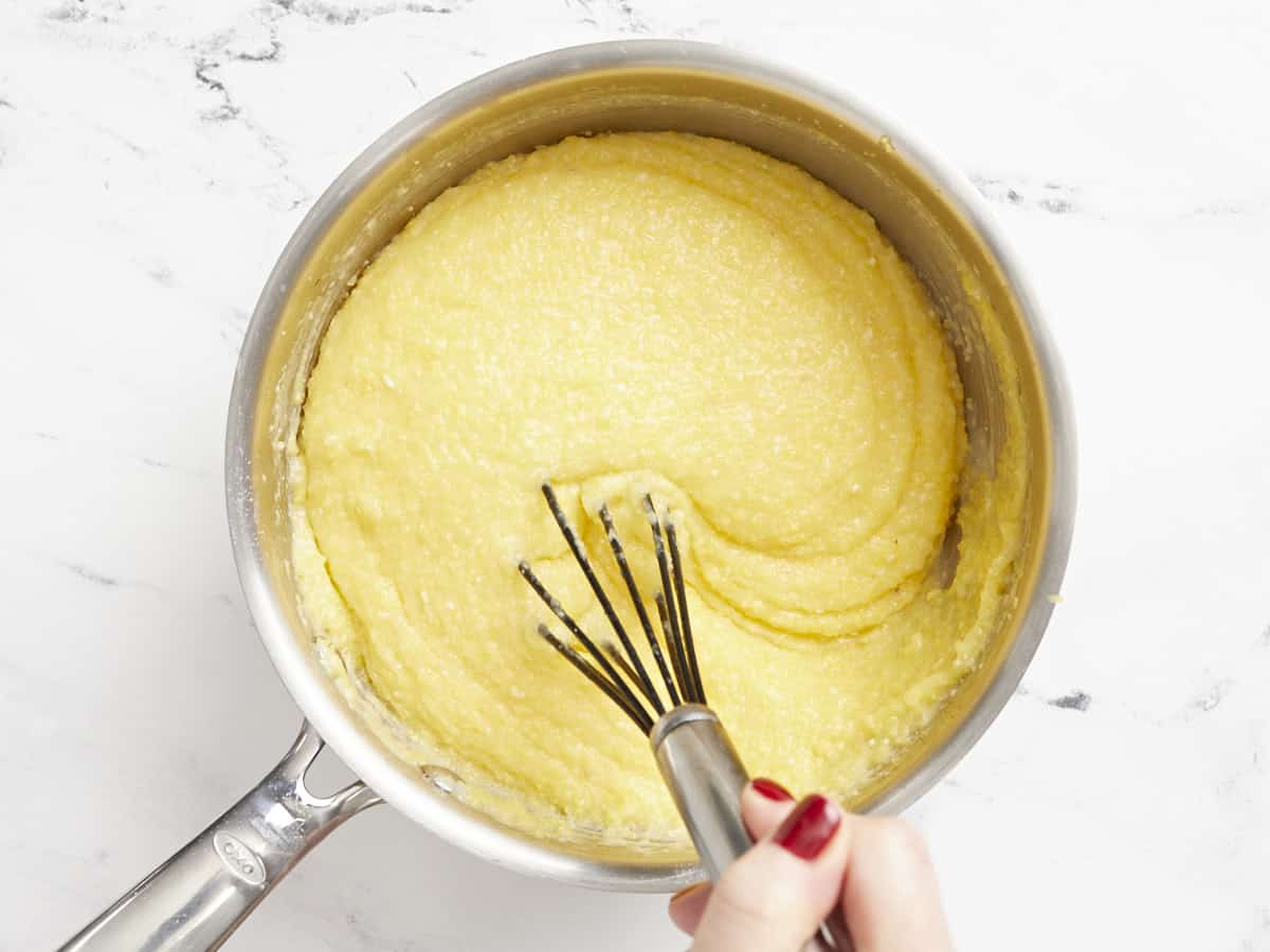Finished creamy polenta being stirred with a whisk.