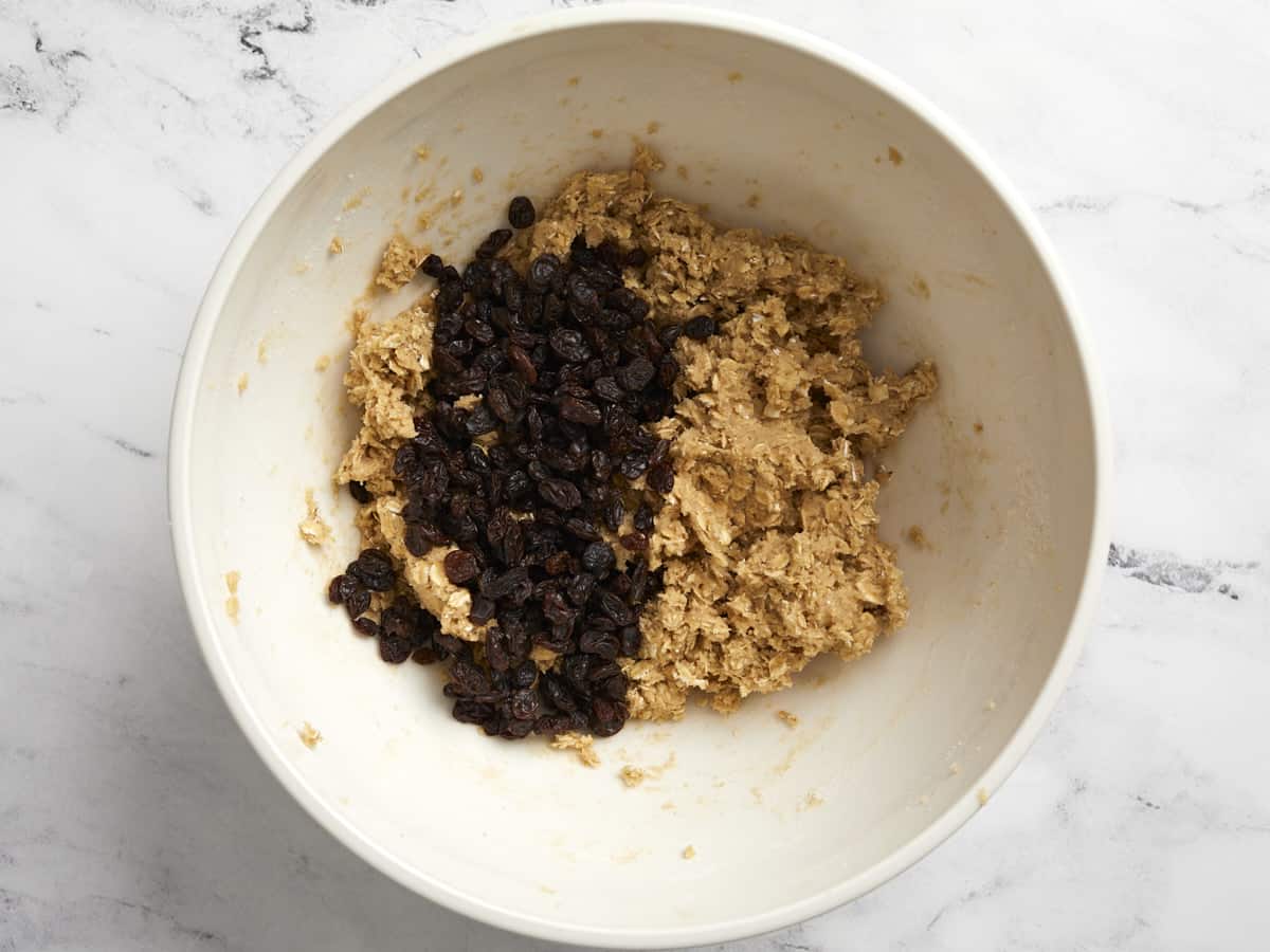Raisins added to cookie batter in a bowl.