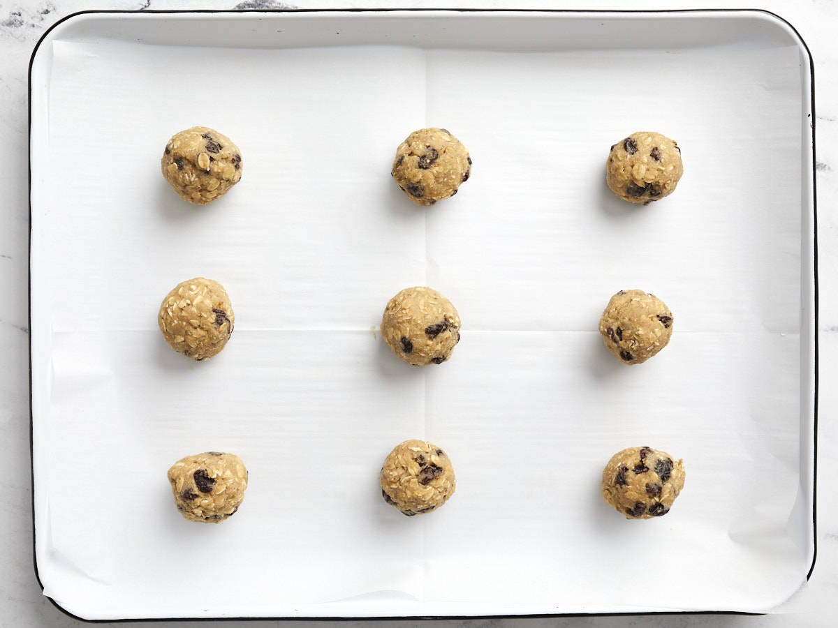 Cookie dough shaped on a parchment lined baking sheet.