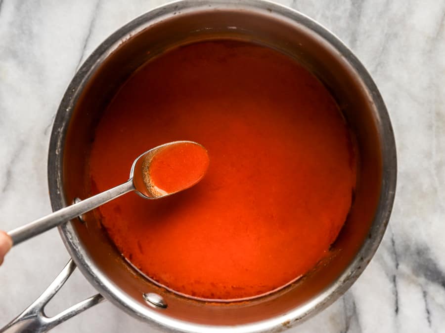 buffalo sauce in a saucepan with a spoon.