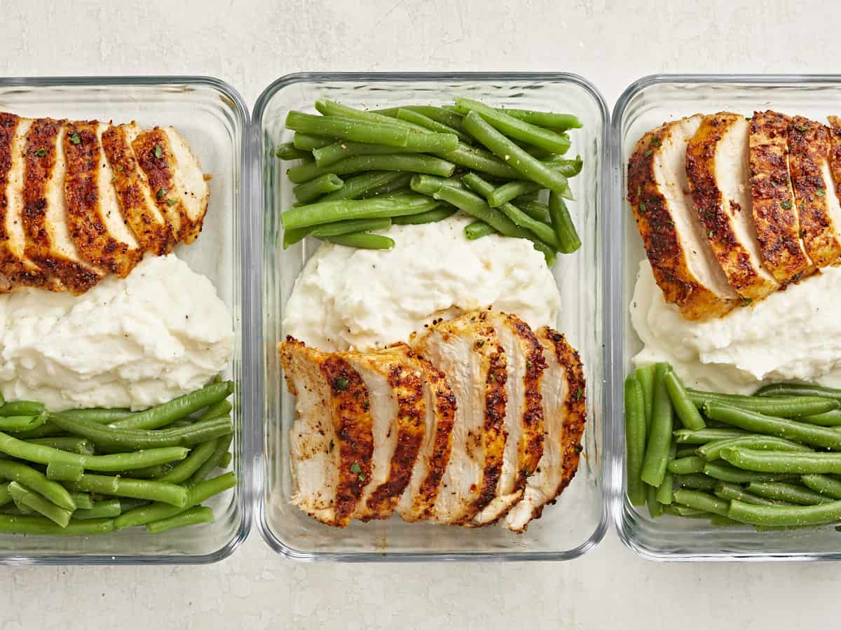 Air Fryer Chicken Breast sliced in meal prep containers with green beans and mashed potatoes on the side.