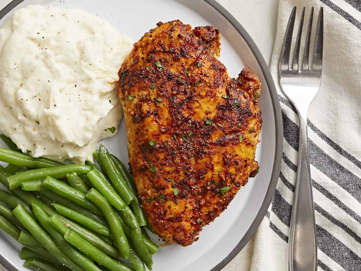 Overhead view of Air Fryer Chicken Breast on a plate with a side of mashed potatoes and green beans.
