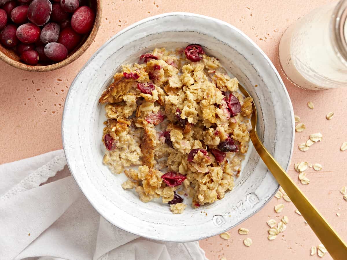 Overhead view of cranberry apple baked oatmeal in a bowl with a golden spoon.