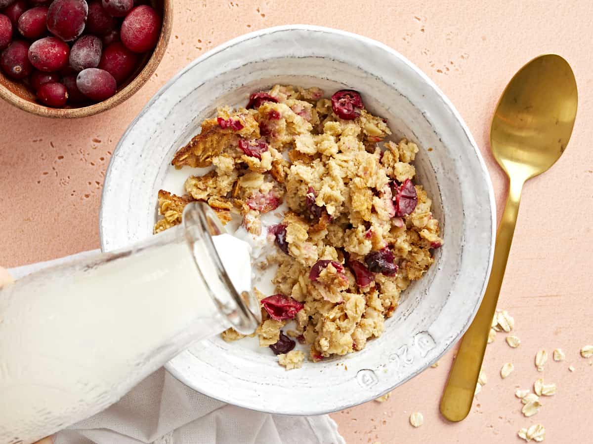 Milk being poured over a bowl of cranberry apple baked oatmeal.