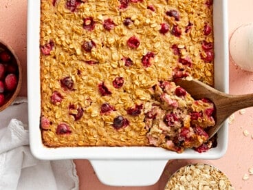 Baked oatmeal being scooped out of the casserole dish with a wooden spoon.