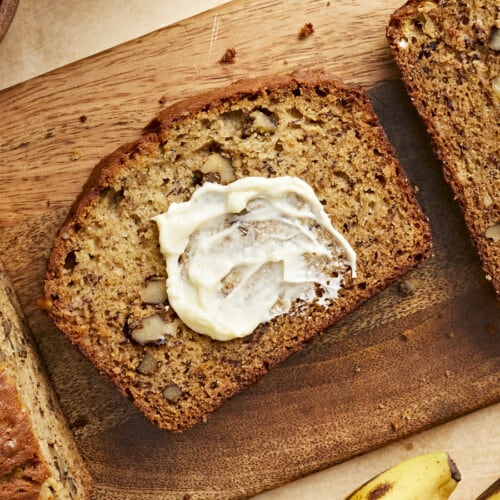 Overhead view of a slice of banana bread with butter spread on it.
