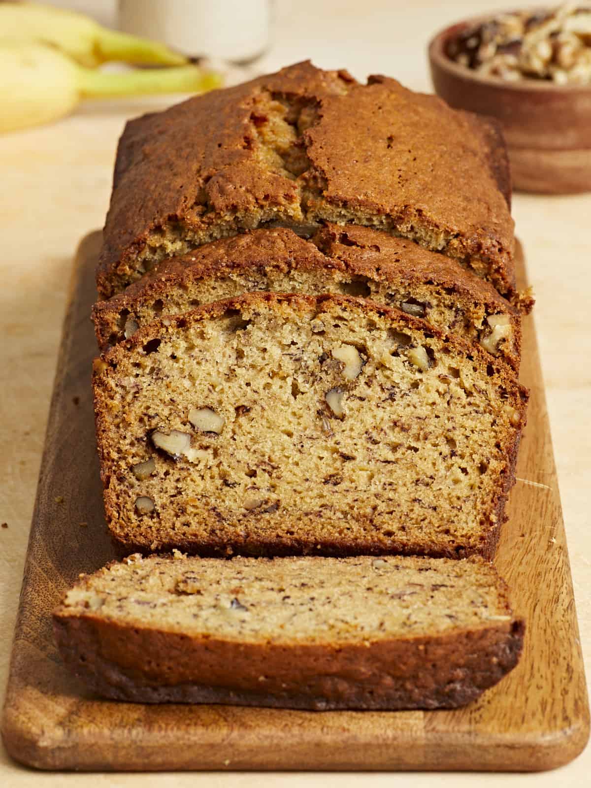 Front view of a sliced loaf of banana bread on a wooden cutting board.