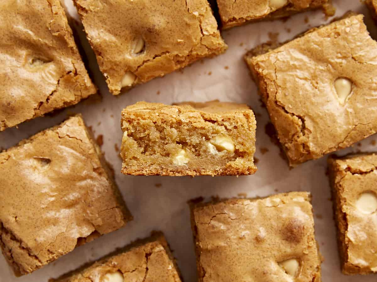 Close up overhead view of blondies on parchment paper with one blondie turned on it's side.