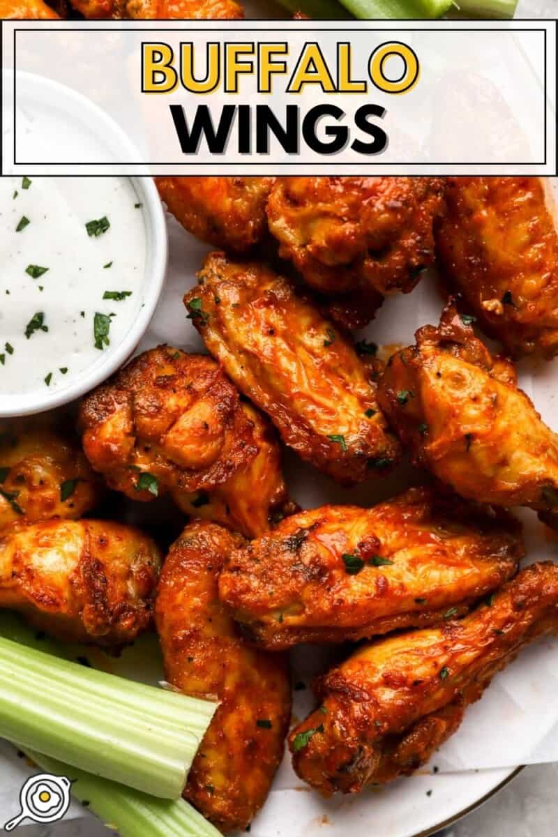 Overhead view of a plate of buffalo wings with a side of ranch dressing and celery sticks on the plate.