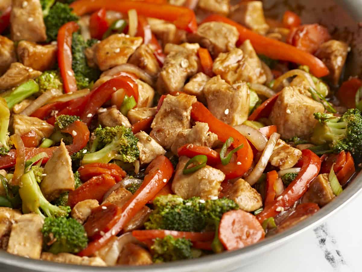 Side close up view of chicken stir fry in a skillet.