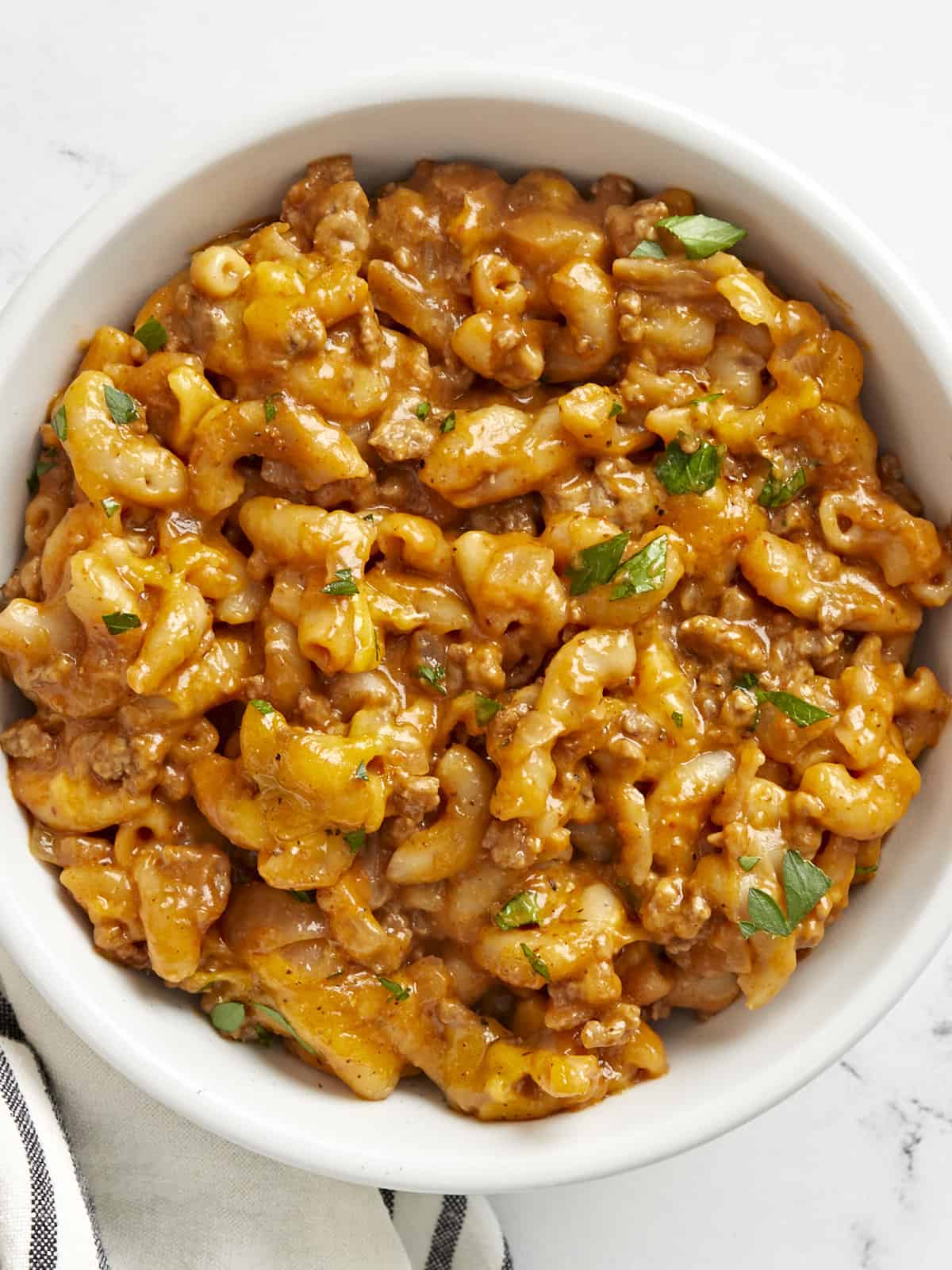 Overhead view of a bowl full of chili mac, garnished with parsley.