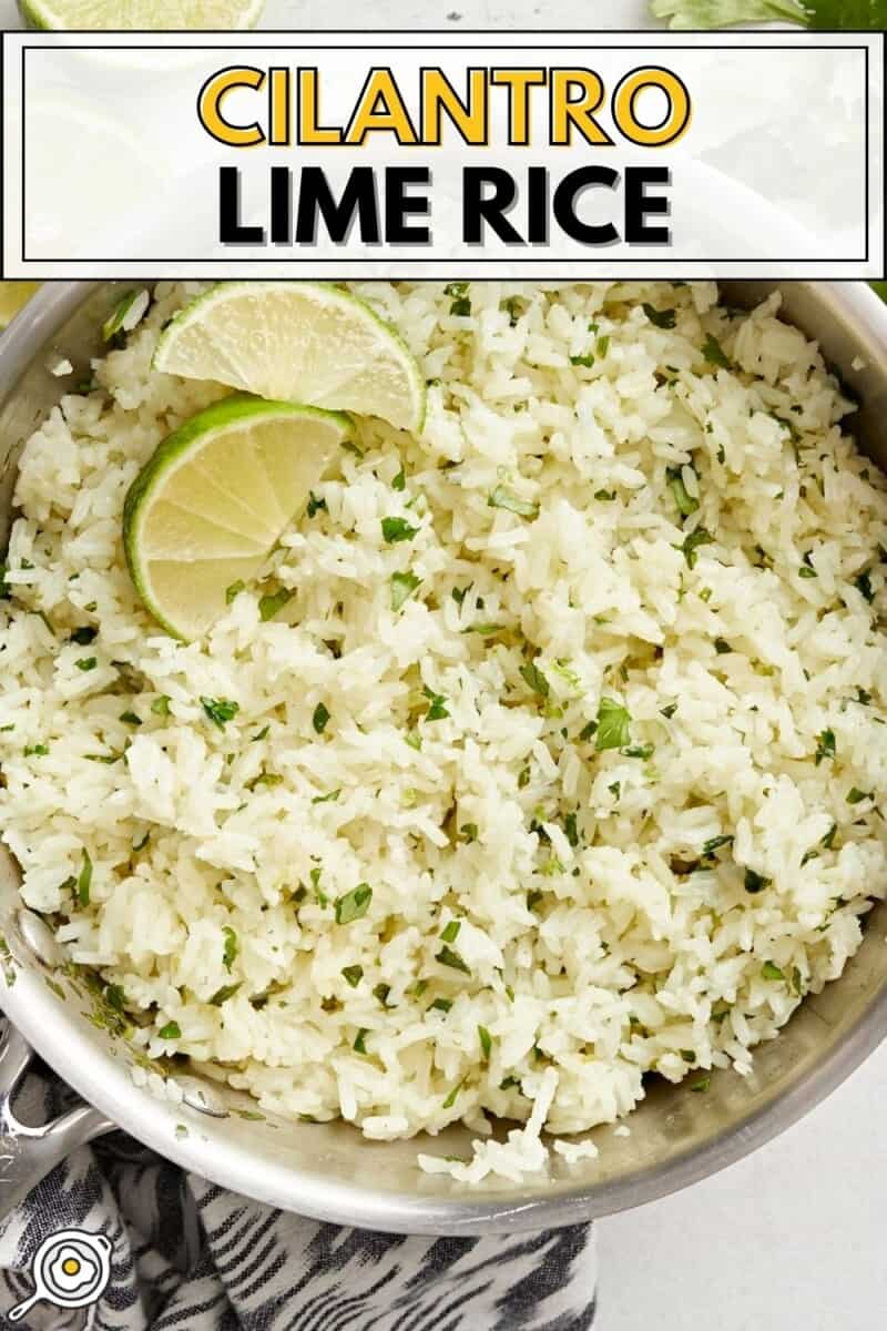 Overhead view of a pot of cilantro lime rice with lime wedges as garnish.