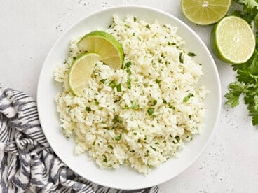Overhead view of a bowl of cilantro lime rice with lime wedges as garnish.