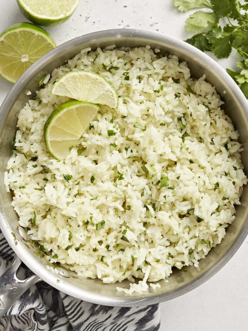 Close up overhead view of cilantro lime rice in the pot with lime garnishes.