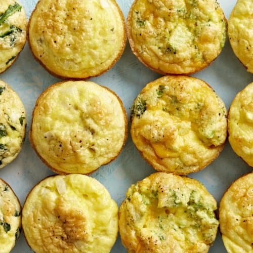 Cooked egg muffins lined up in a grid on a blue surface.