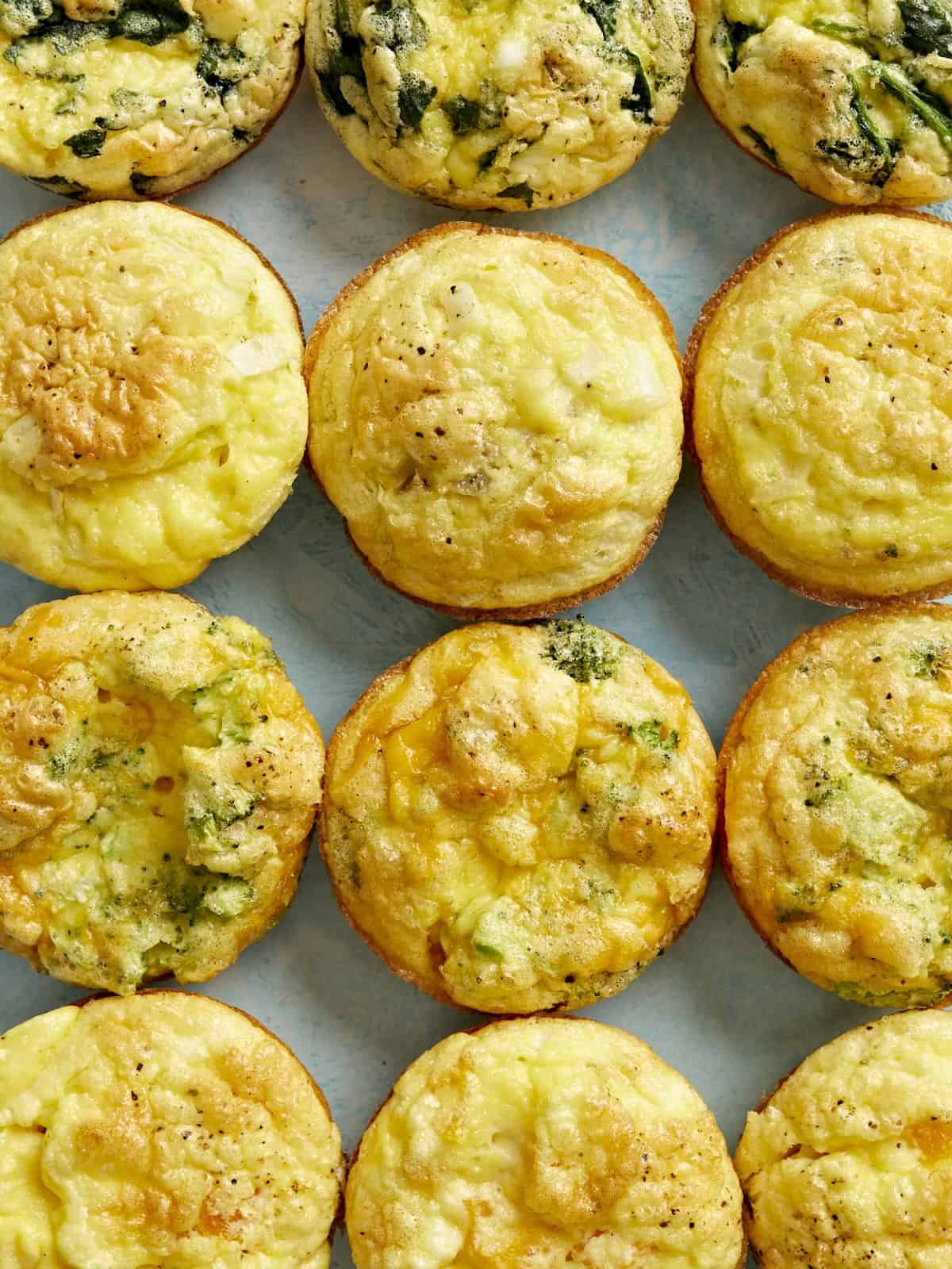 Overhead view of egg muffins lined up in a grid on a blue background.