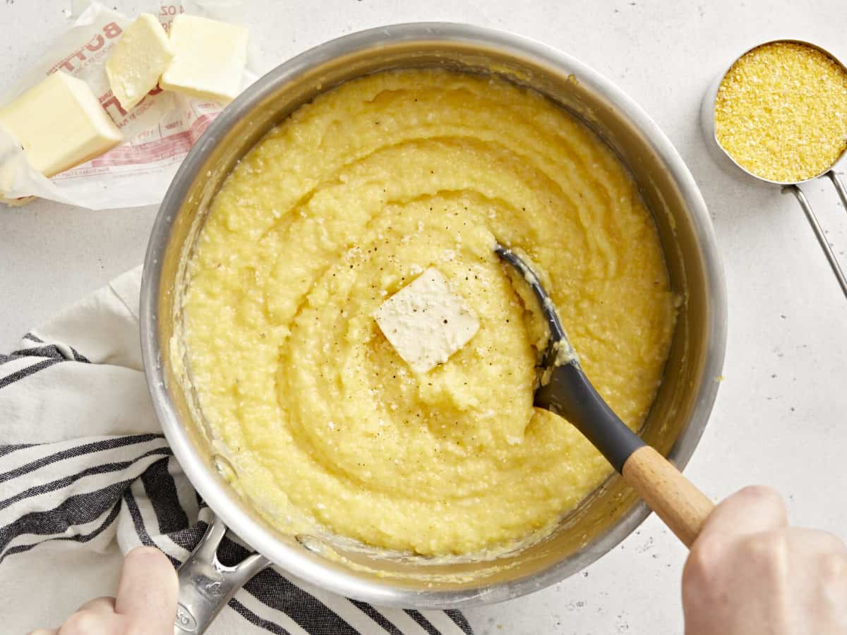 Overhead view of polenta in a pot with butter being stirred.