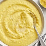 Close up of polenta in a bowl with a spoon dug into the side.