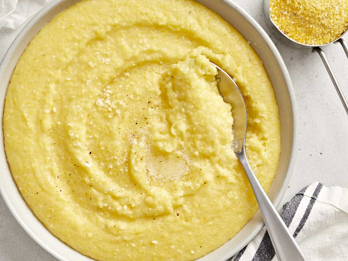 Close up of polenta in a bowl with a spoon dug into the side. 