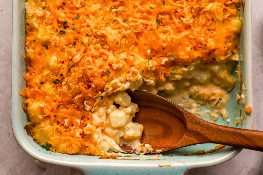 close up view of a wooden spoon in potato casserole.