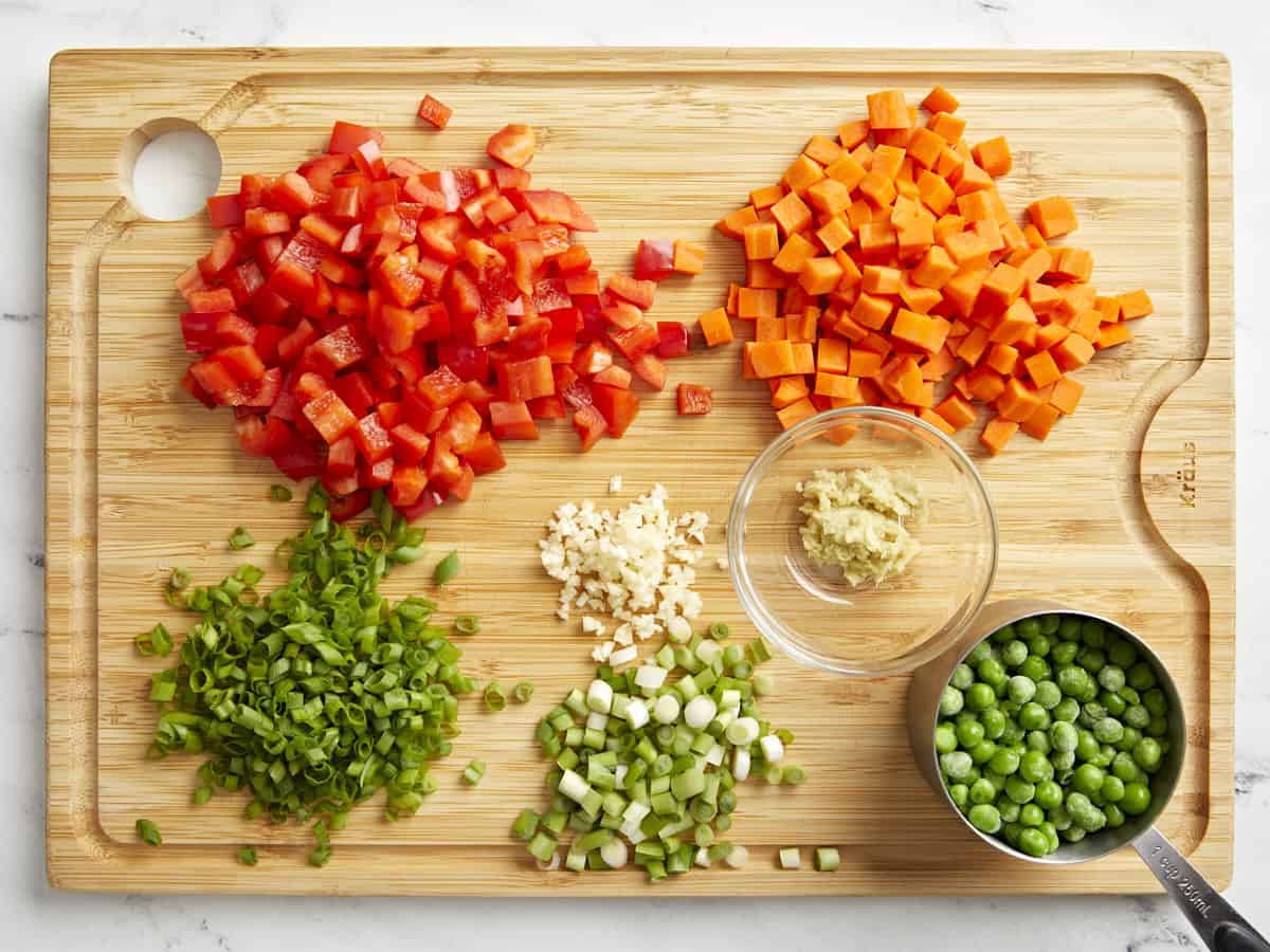 Chopped vegetables for chicken fried rice on a cutting board.