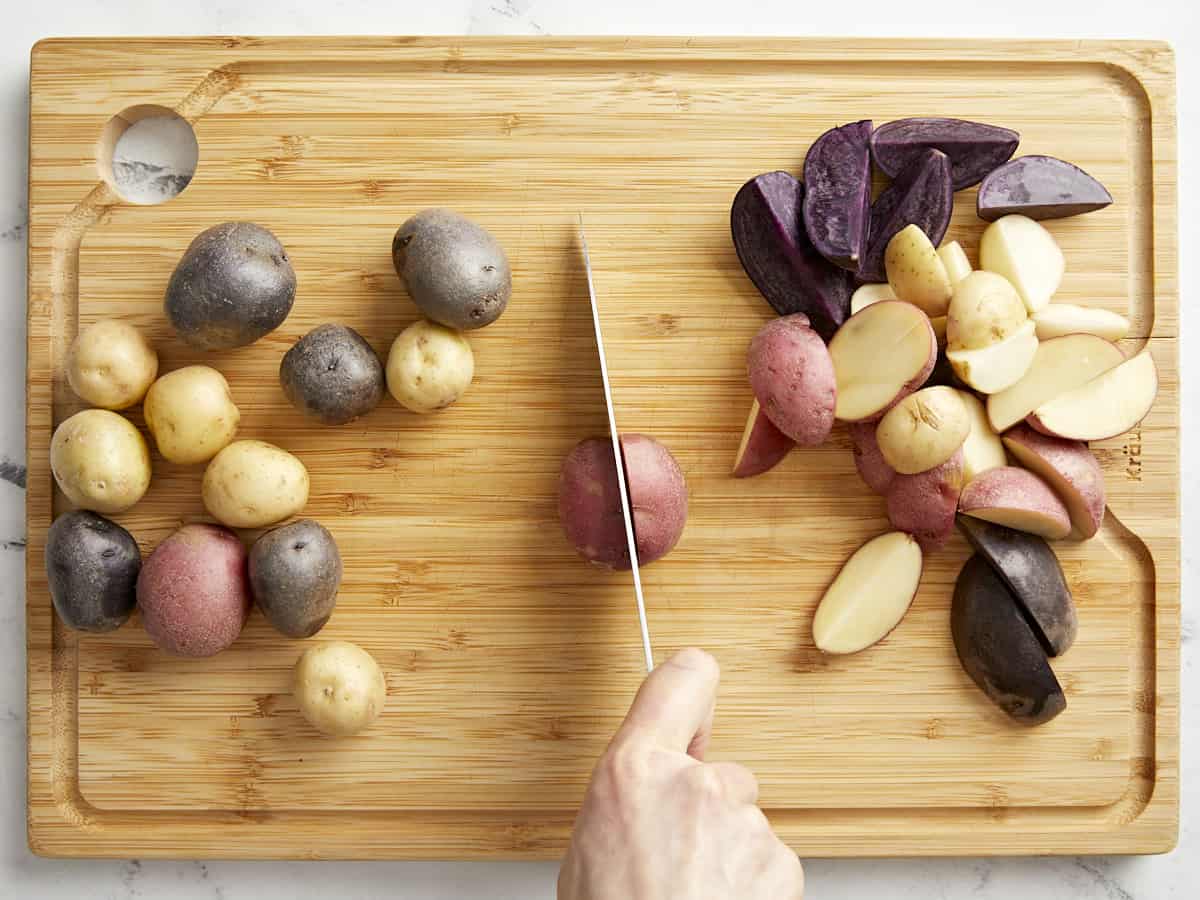 cutting tricolored potatoes on a bamboo cutting board.