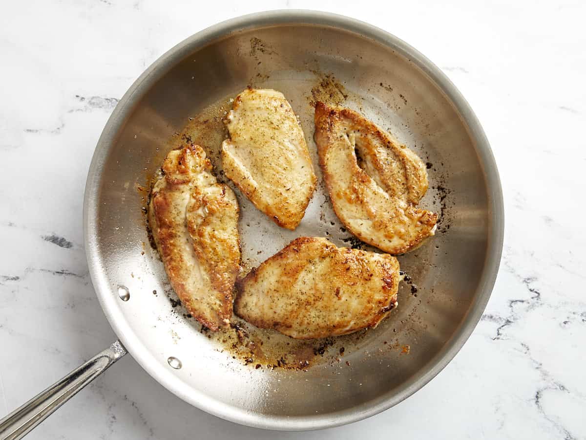 Chicken breasts seared in a skillet.