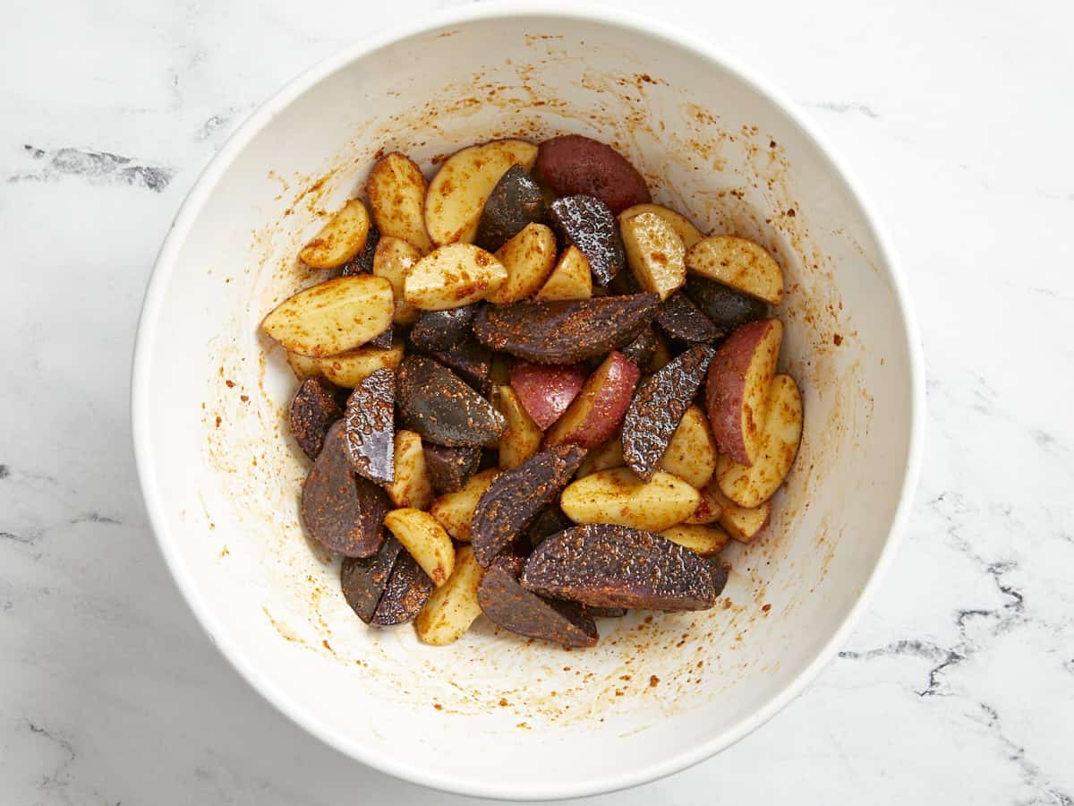 seasoned potato wedges in a white bowl.