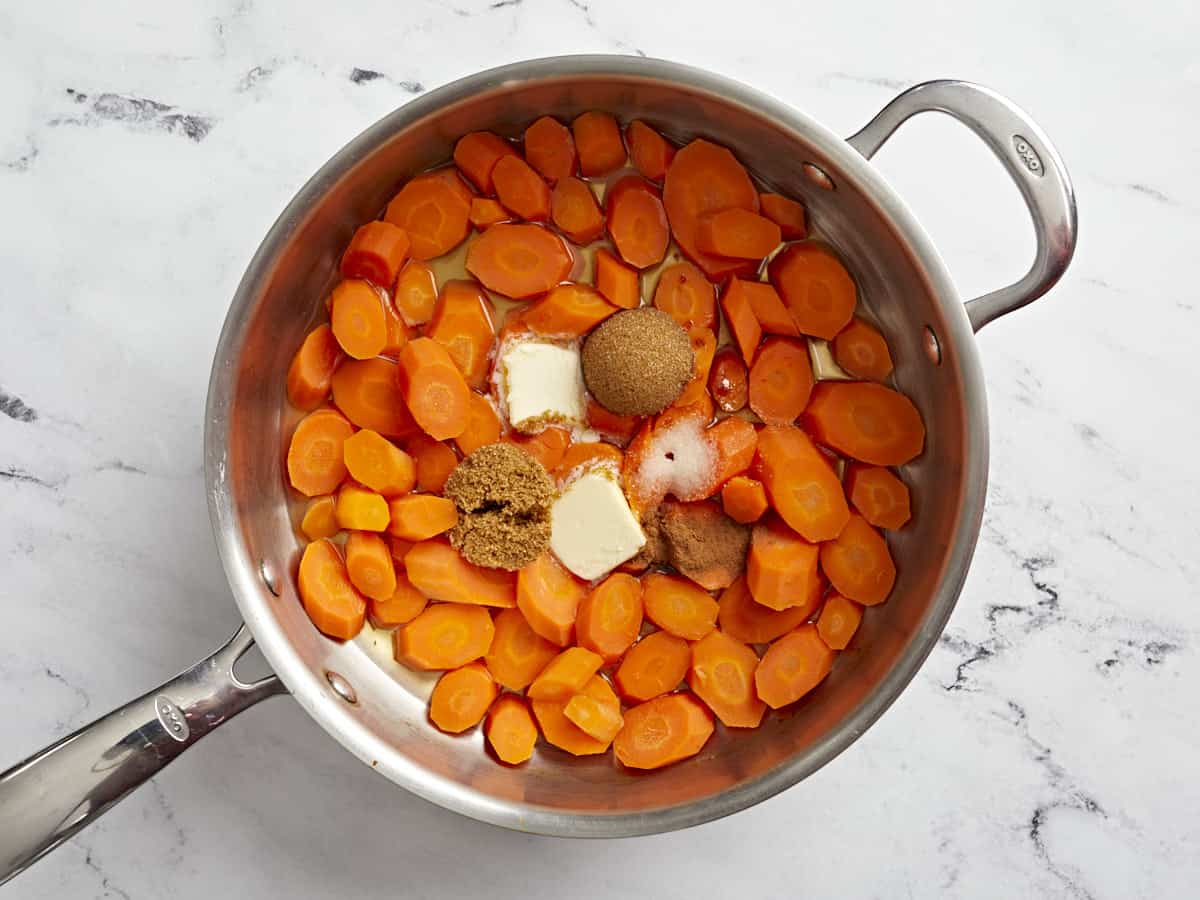 Carrots in a sauté pan with butter, brown sugar, salt, and cinnamon added.