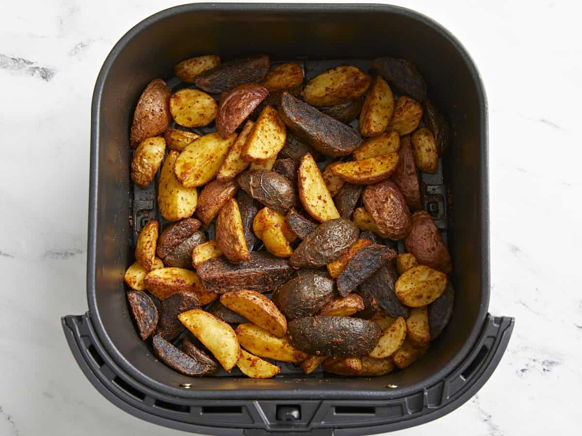 seasoned potatoes in an air fryer basket.