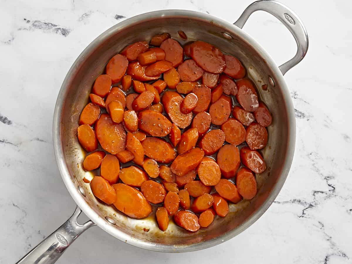 Overhead view of cooked glazed carrots in a sauté pan.