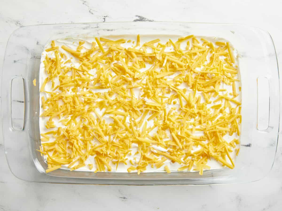 Shredded cheese added evenly on top of sour cream layer.