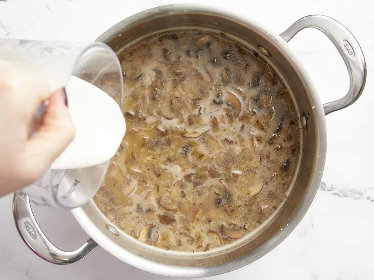 Heavy cream being poured into the soup.