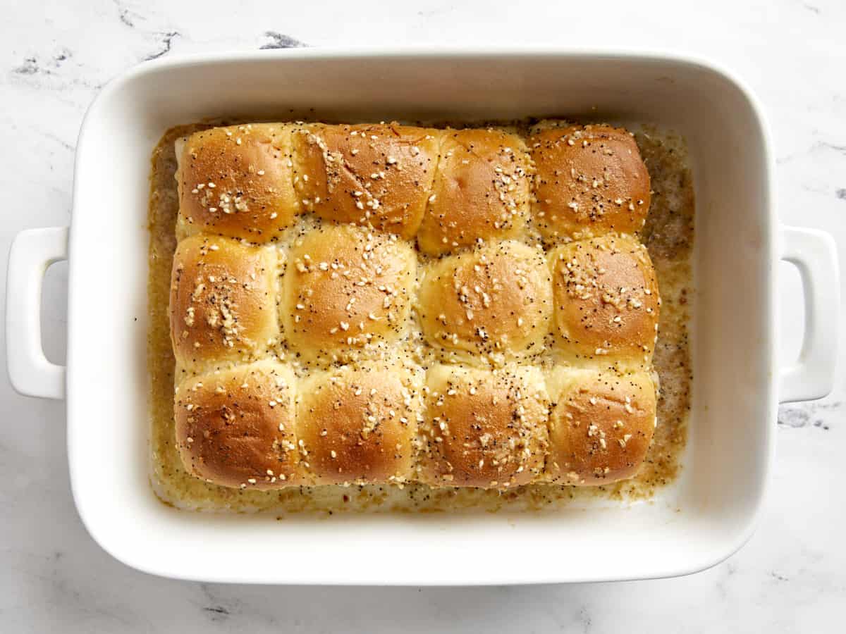 Overhead view of baked ham and cheese sliders in a white baking dish.