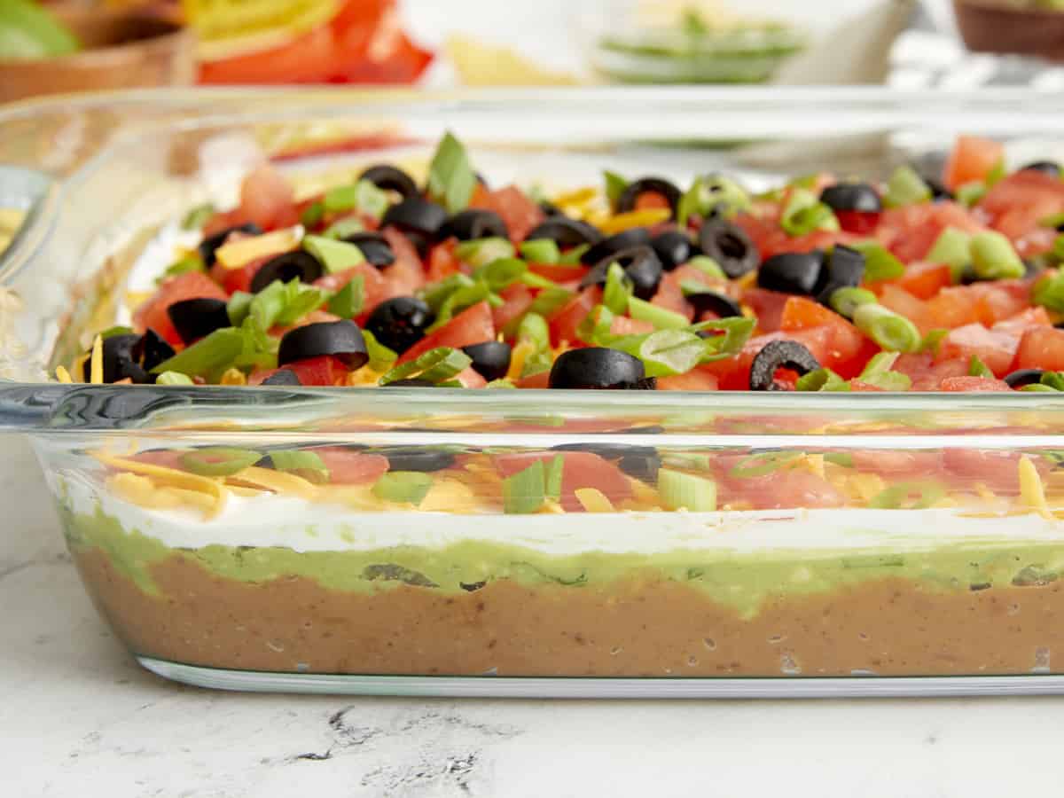 Side close up view of 7 layer dip in a glass casserole dish.