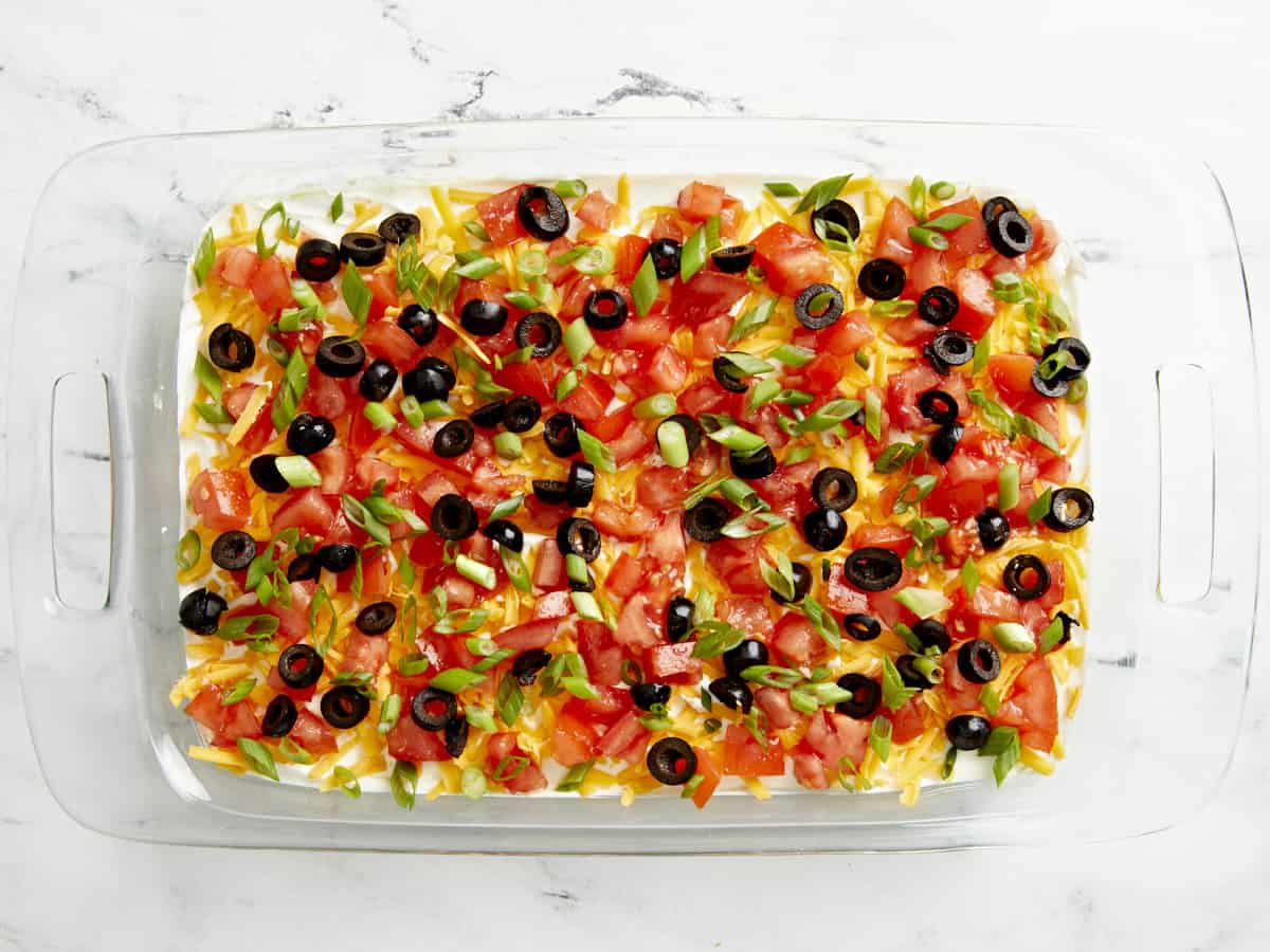 Chopped tomatoes, black olives, and sliced green onions added and spread out evenly on top of shredded cheese layer.