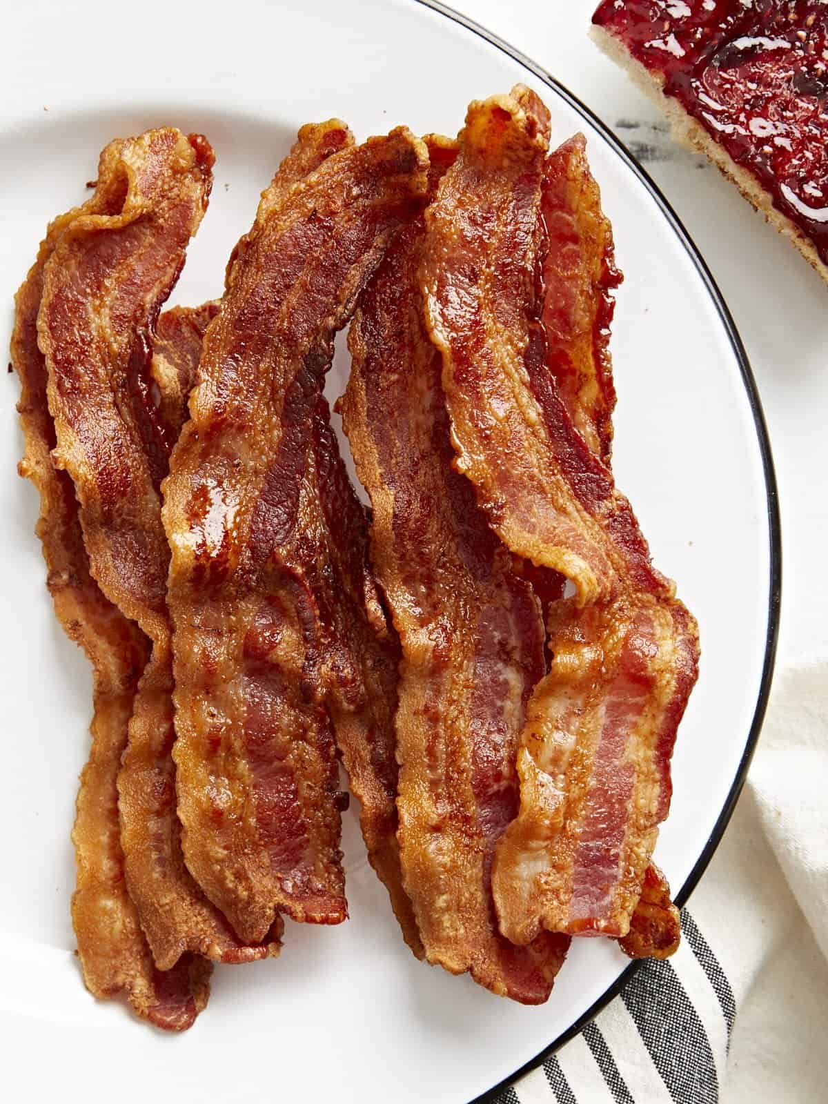 Overhead view of Air Fryer Bacon strips on a white serving plate.