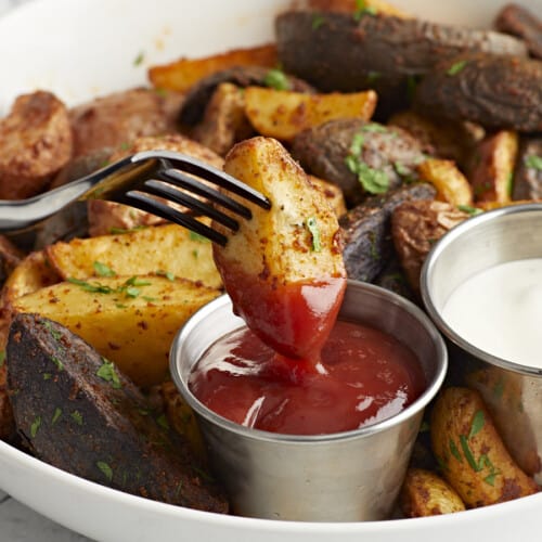 fork dipping an air fryer potato into ketchup.